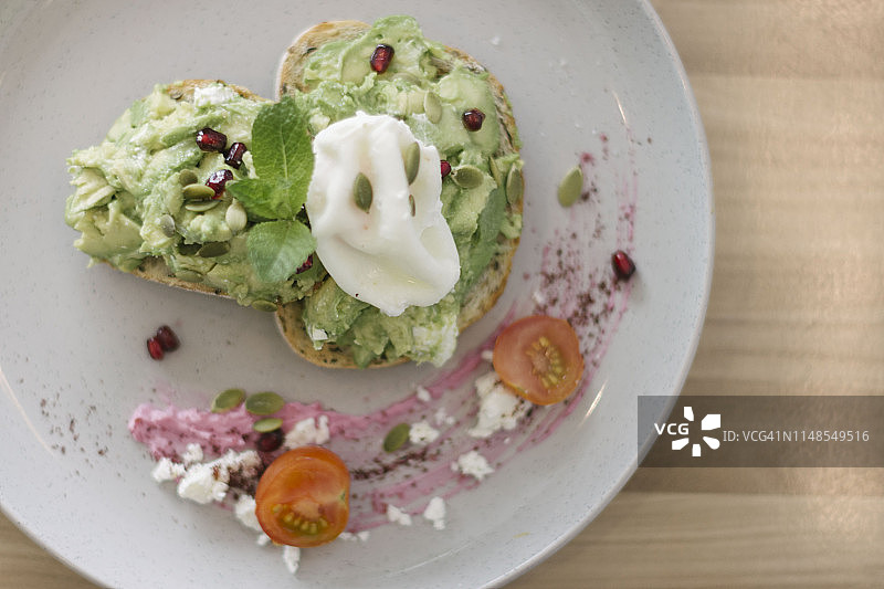 牛油果、水波蛋、羊乳酪、小番茄和石榴吐司早餐图片素材