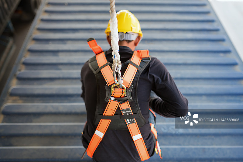 在高处作业时佩戴安全带和安全绳的建筑工人图片素材