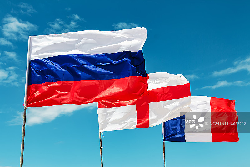 蓝天下迎风飘扬的俄罗斯、英国和法国国旗图片素材