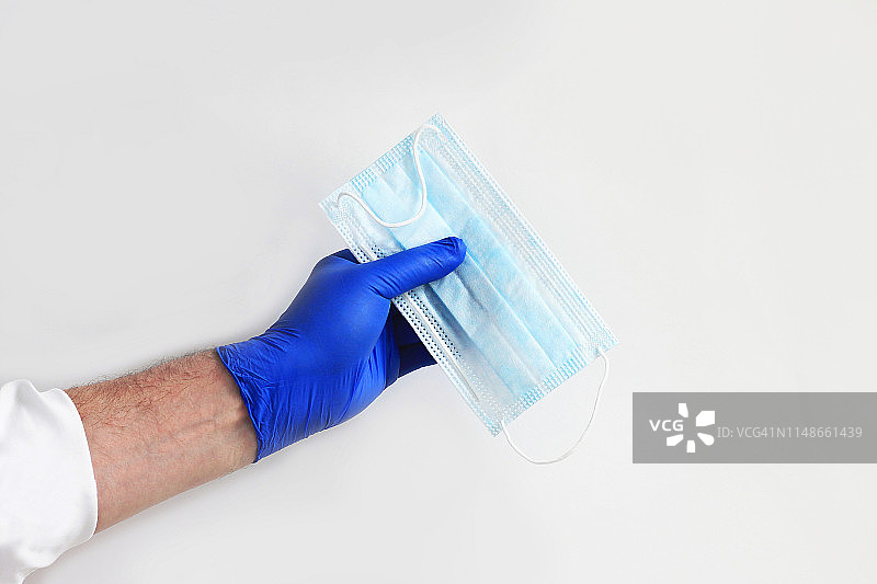 戴蓝色手套的手持医用口罩图片素材