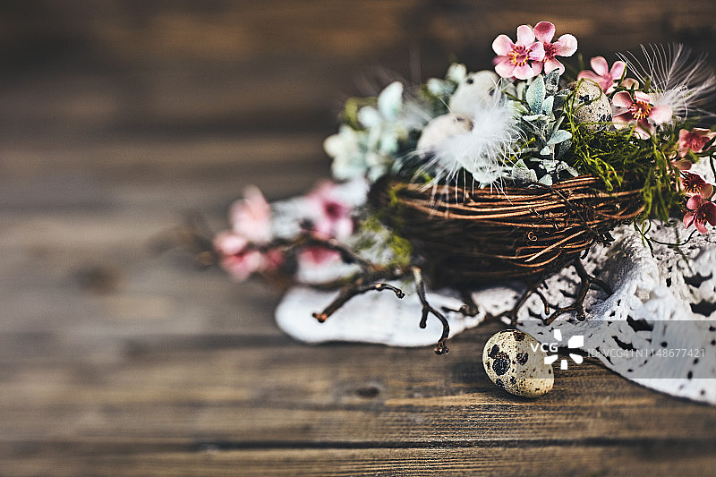 乡村木桌上，花朵和羽毛点缀的鸟巢与鹌鹑蛋图片素材