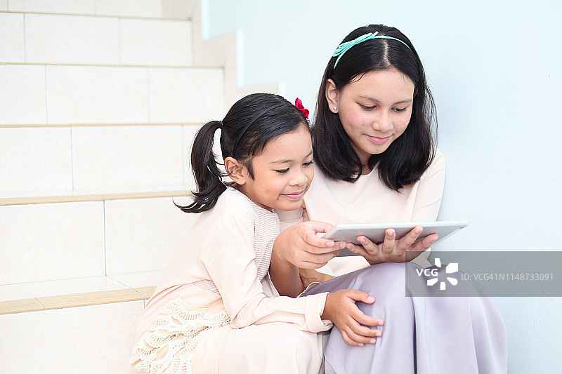 姐妹俩在开斋节使用平板电脑图片素材