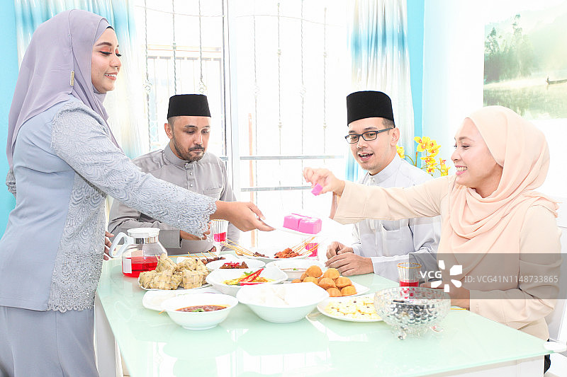 一群穿着开斋节传统服装的马来成年人享用开斋节菜肴图片素材