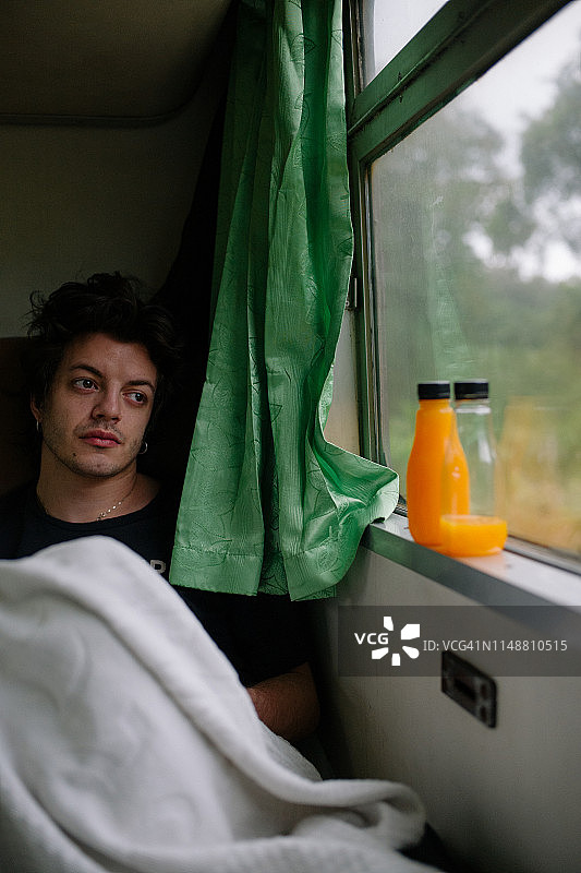 在泰国，看着火车窗外的年轻男人图片素材