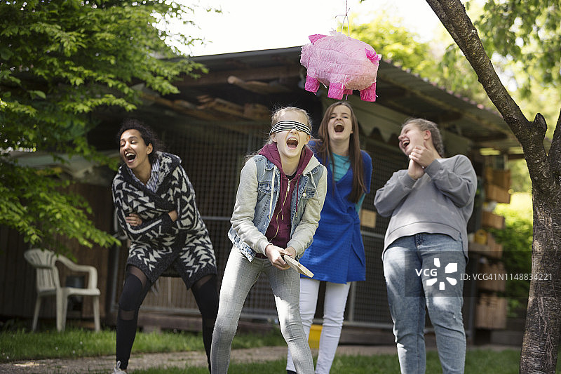一群欢笑的女孩玩粉色小猪形状的彩罐图片素材