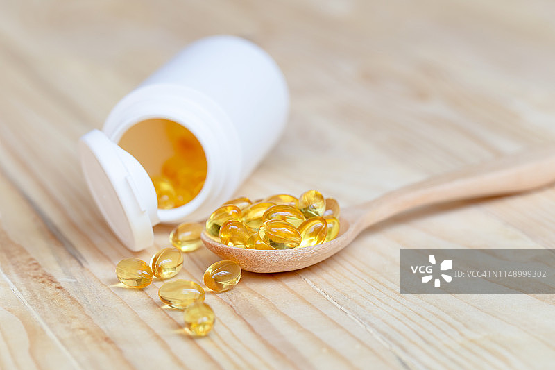 木勺上含Omega 3和维生素D的鱼油胶囊，健康饮食理念图片素材