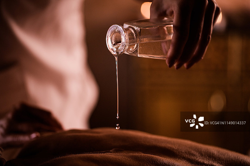 在水疗中心倒入按摩油的特写图片素材