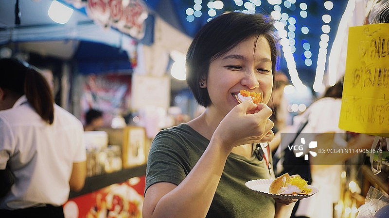 在夜市品尝美食的女游客图片素材