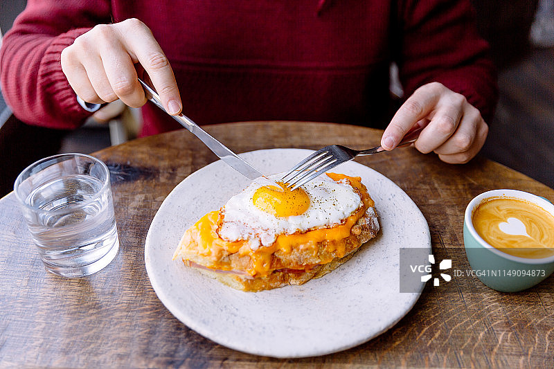 男人吃涂有奶酪和煎蛋的克罗克夫人三明治图片素材