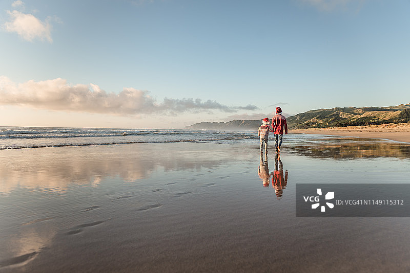 兄弟戴着圣诞帽在海滩上手牵着手图片素材