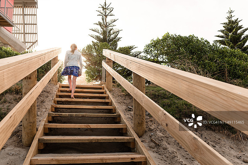 在海滩木梯上行走的金发女孩图片素材