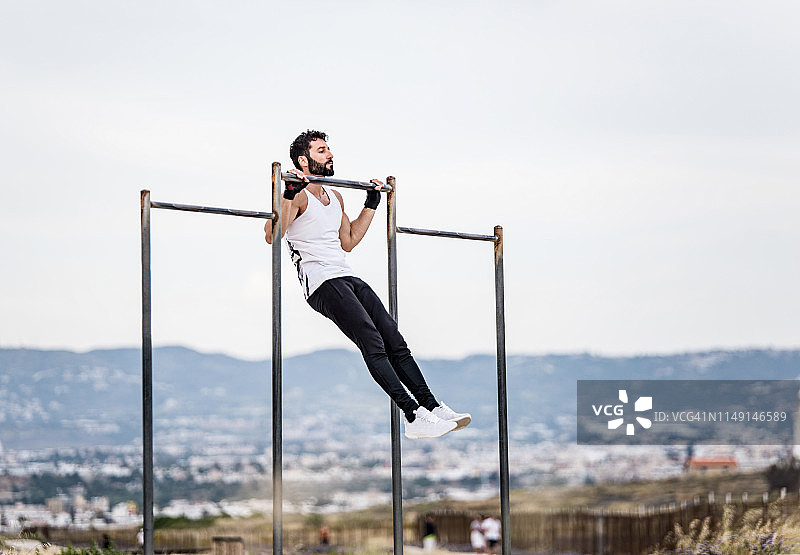 在户外做引体向上的年轻运动男子图片素材
