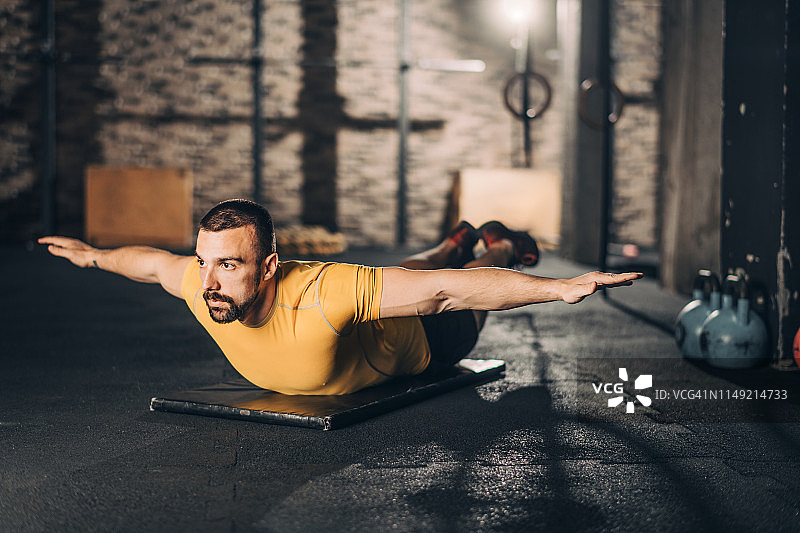 健壮的运动员在健身房锻炼前做热身，进行交替超人平板支撑图片素材