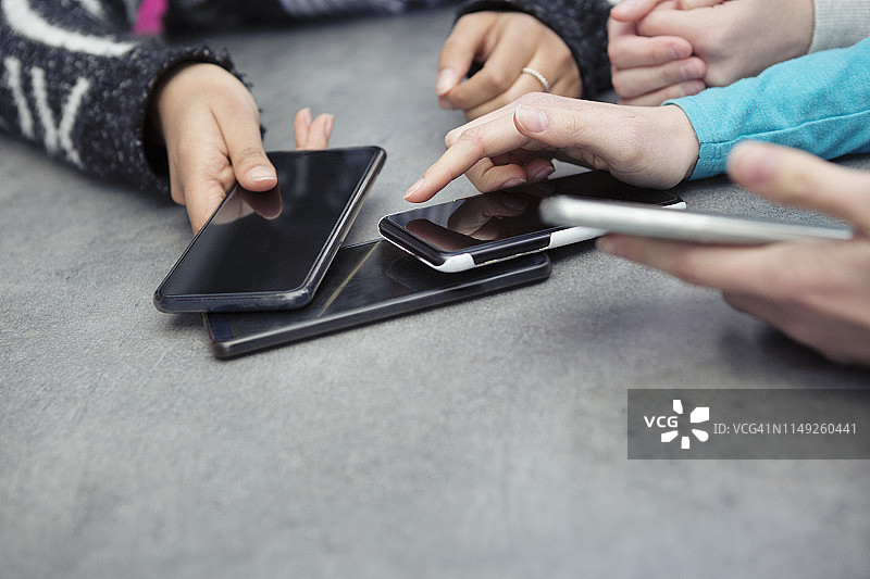 三人在桌上用手机分享充电图片素材