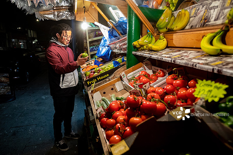 青年男子在夜间当地商店购物图片素材
