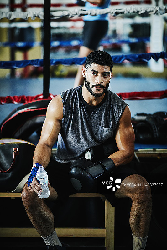 在拳击馆训练期间休息的出汗的男拳击手肖像图片素材