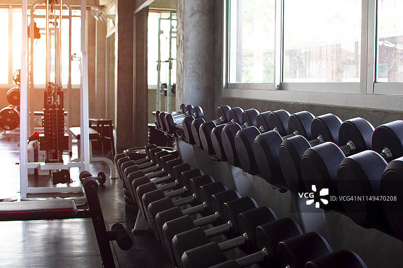 健身房里，运动器材概念哑铃在架子上的柔焦照片。图片素材