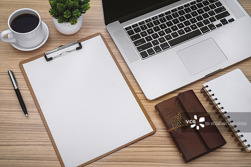 工作桌上的剪贴板、笔记本电脑和记事本上的纸张图片素材