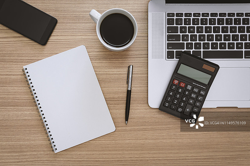 木制办公桌上的笔记本电脑、计算器和记事本图片素材