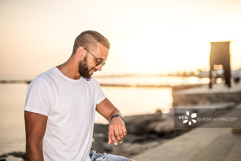 快乐的年轻男人查看智能手表上的时间图片素材