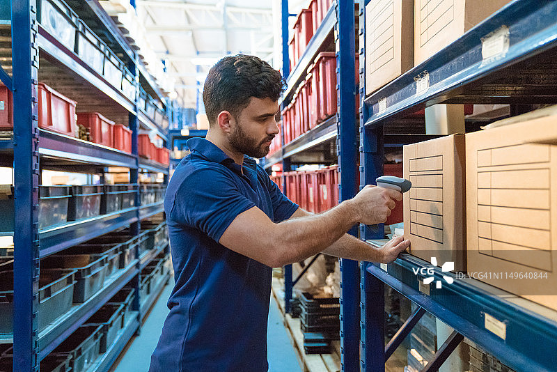 扫描运输纸板箱的年轻男性工人图片素材