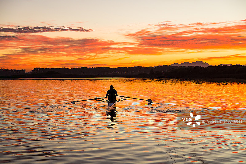 中年男人在黎明时划单人双桨图片素材