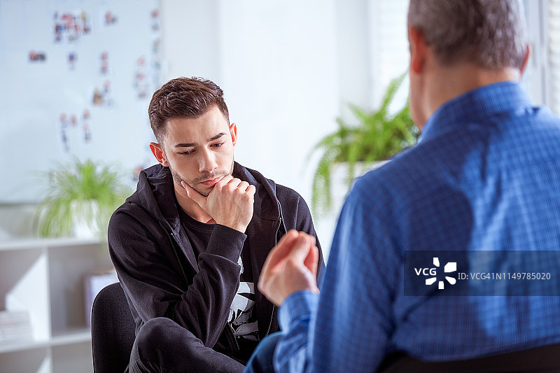 男学生在咨询中听治疗师讲话图片素材
