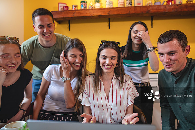 笑容满面的工作伙伴们正在给同事写一封有趣的邮件图片素材