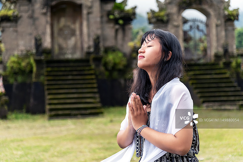 年轻女子在新布扬湖印度教寺庙中，双手合十，呈瑜伽姿势图片素材