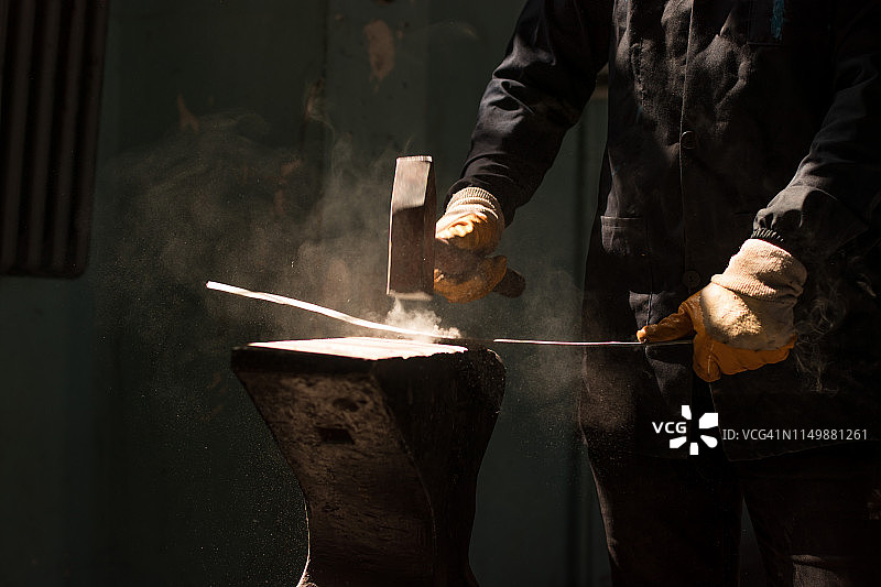 铁匠在铁砧上锻造铁条图片素材