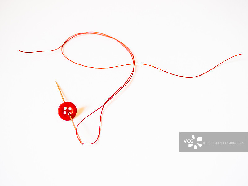 带有红线和纽扣的针。图片素材