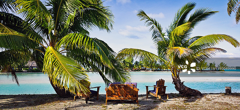 蓝色海滩边的棕榈树和户外躺椅图片素材