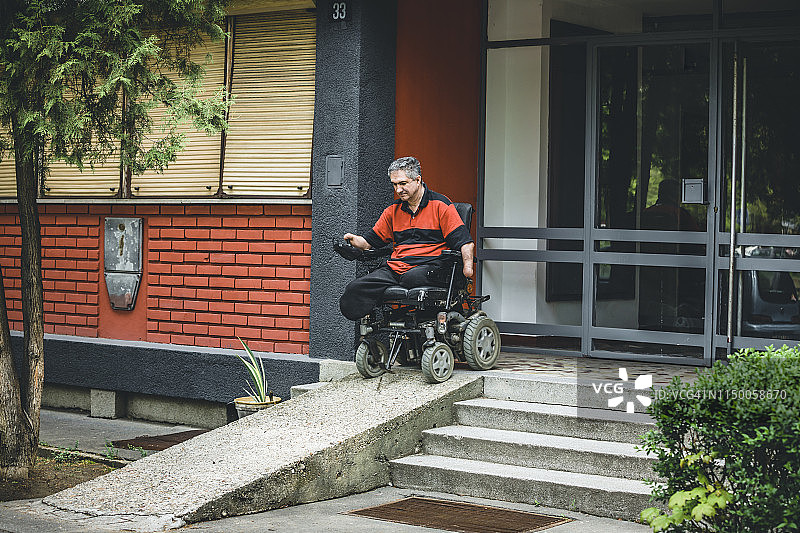 乘坐电动轮椅离开建筑物的男人图片素材