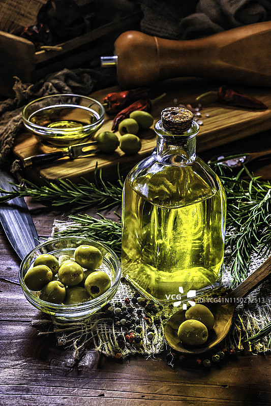橄榄油瓶和橄榄，摆放在复古乡村厨房的桌子上图片素材