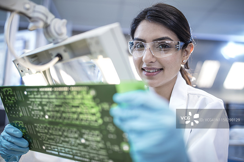 女技术员手持主板的微笑合影图片素材