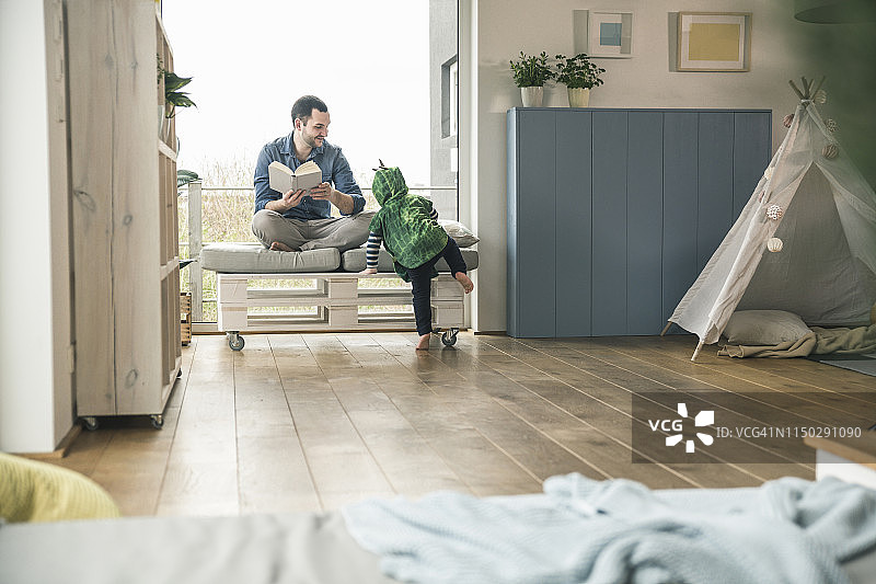 穿着戏服的男孩和父亲在家读书图片素材