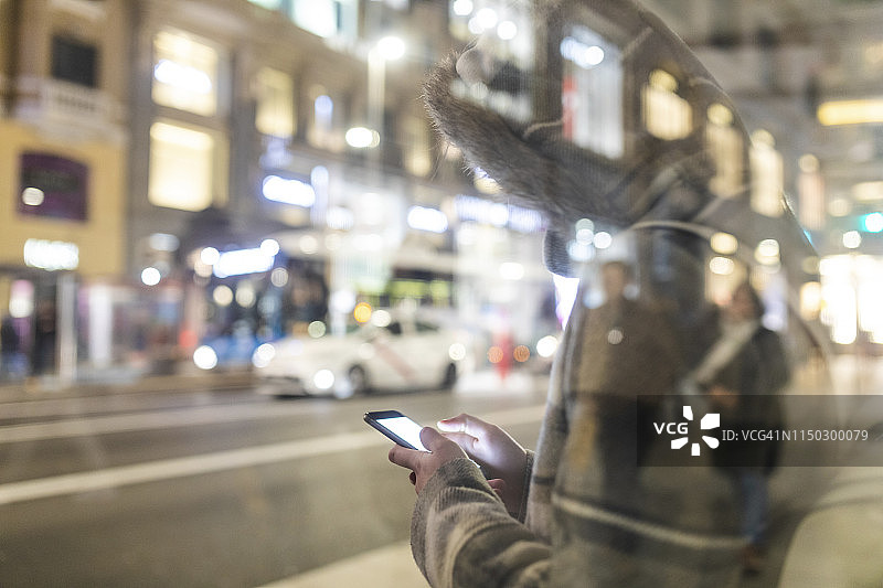 西班牙马德里：在格兰大道旁使用智能手机的年轻女子图片素材