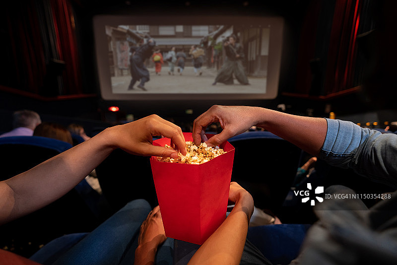 情侣在电影院吃爆米花特写图片素材