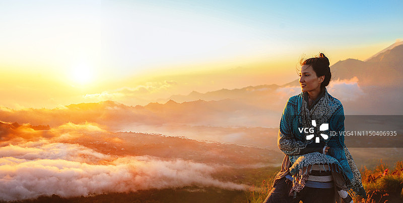 年轻女子在巴厘岛火山顶的云层上旅行图片素材