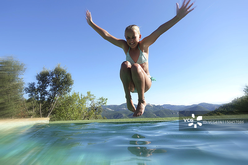 张开双臂跳入游泳池的年轻女孩图片素材
