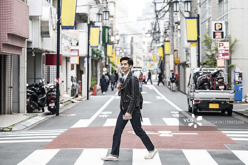 身穿皮夹克走在斑马线上的年轻日本男子图片素材