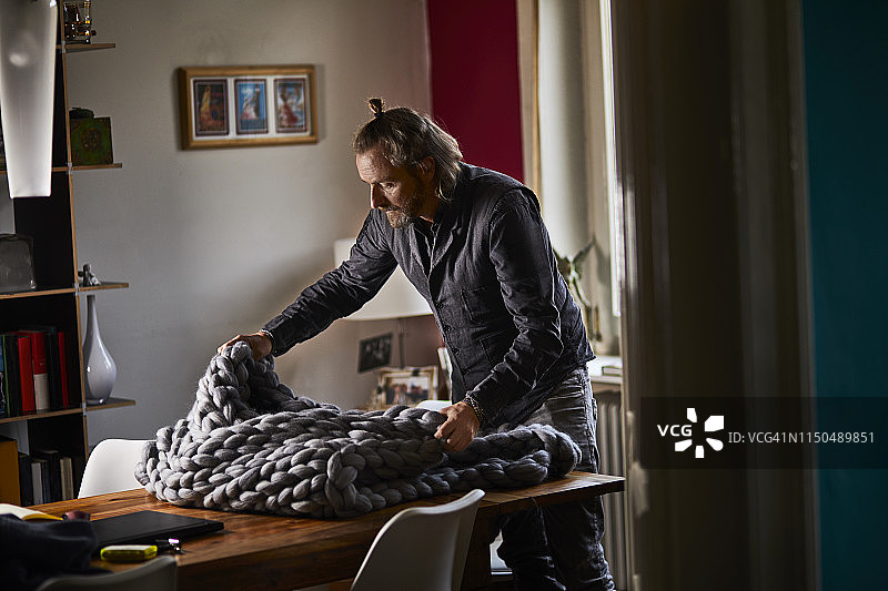 中年男人在家中桌上放着蓬松的毯子图片素材