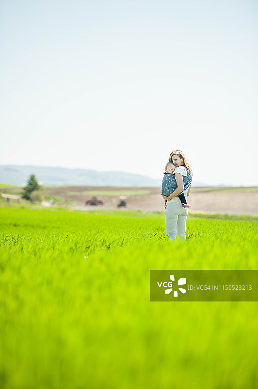 白人母亲用吊带抱着儿子站在托斯卡纳的田野里图片素材