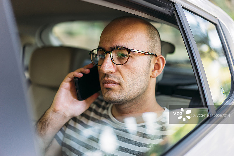 在汽车后座使用手机的男人图片素材