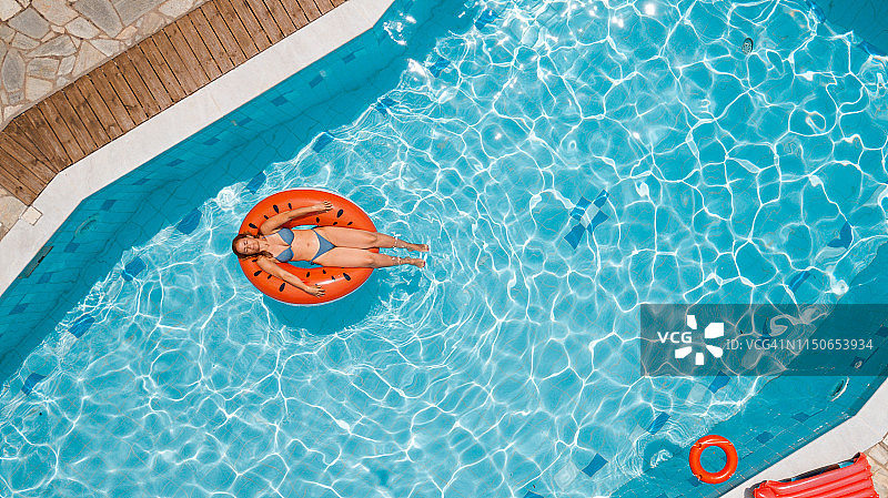 身穿比基尼的女人躺在充气西瓜圈上晒日光浴图片素材
