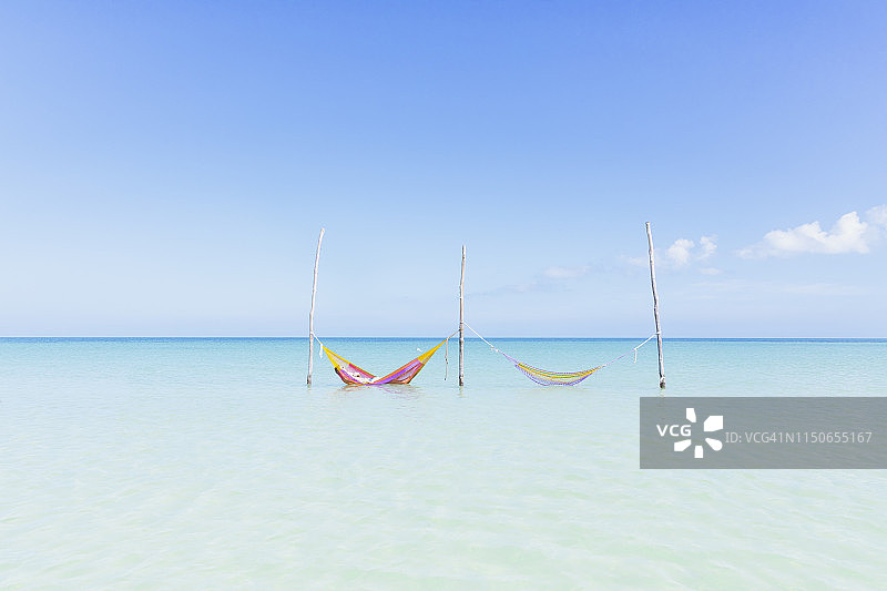 墨西哥霍尔博克斯岛海滩上清澈碧绿的海水中悬挂的两个吊床图片素材