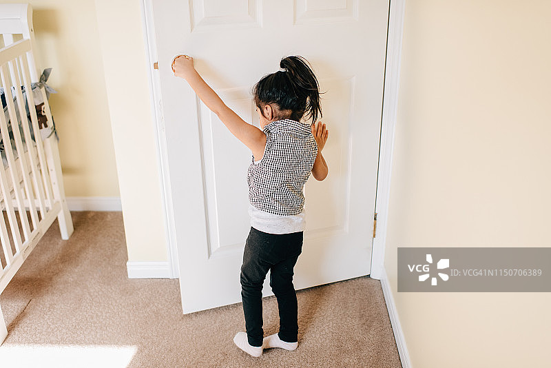 女孩打开育儿室的门，后视图图片素材