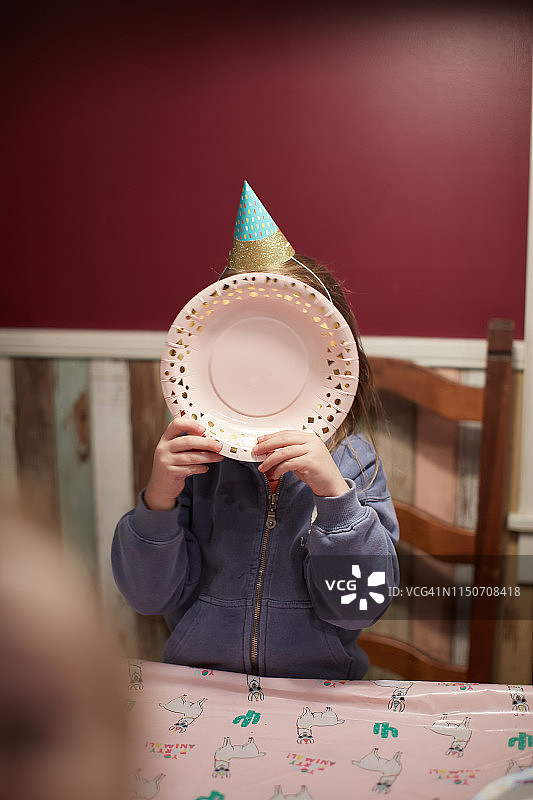 用盘子遮住脸的生日女孩图片素材