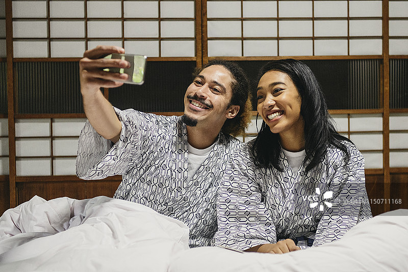 在日式旅馆里，穿着和服的快乐年轻夫妇自拍图片素材