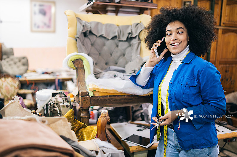 非洲裔女人在车间翻新椅子打电话图片素材